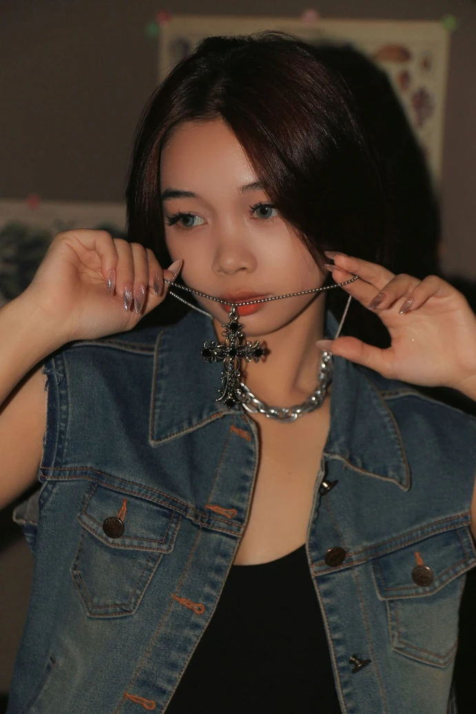 a woman wearing a denim vest and a chain around her neck